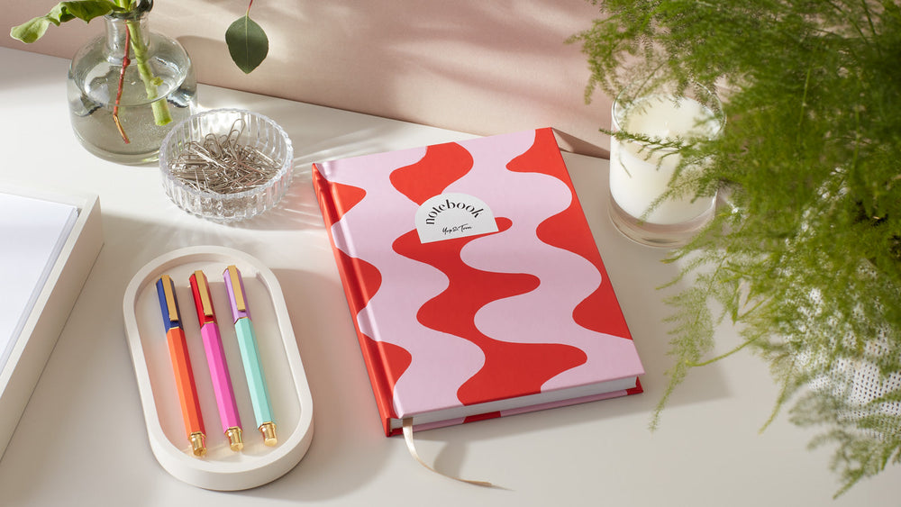 Red and pink A5 notebook with open notebook next to it