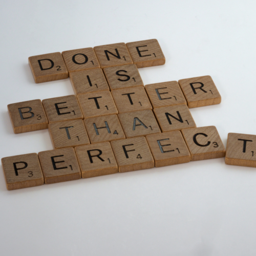 Scrabble tiles showing Done is Better Than Perfect on white background