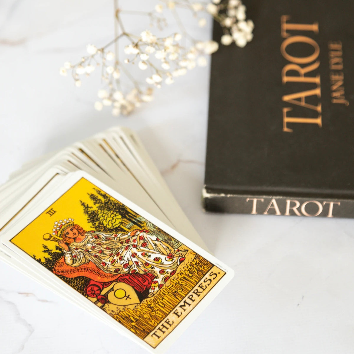 A stack of tarot cards with a tarot book in the background