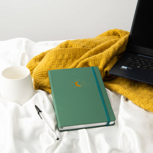 green lined journal lying on bed with pen