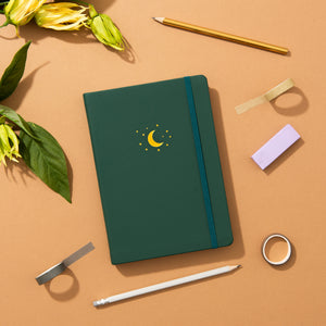 forest green moon and star journal on a table with accessories